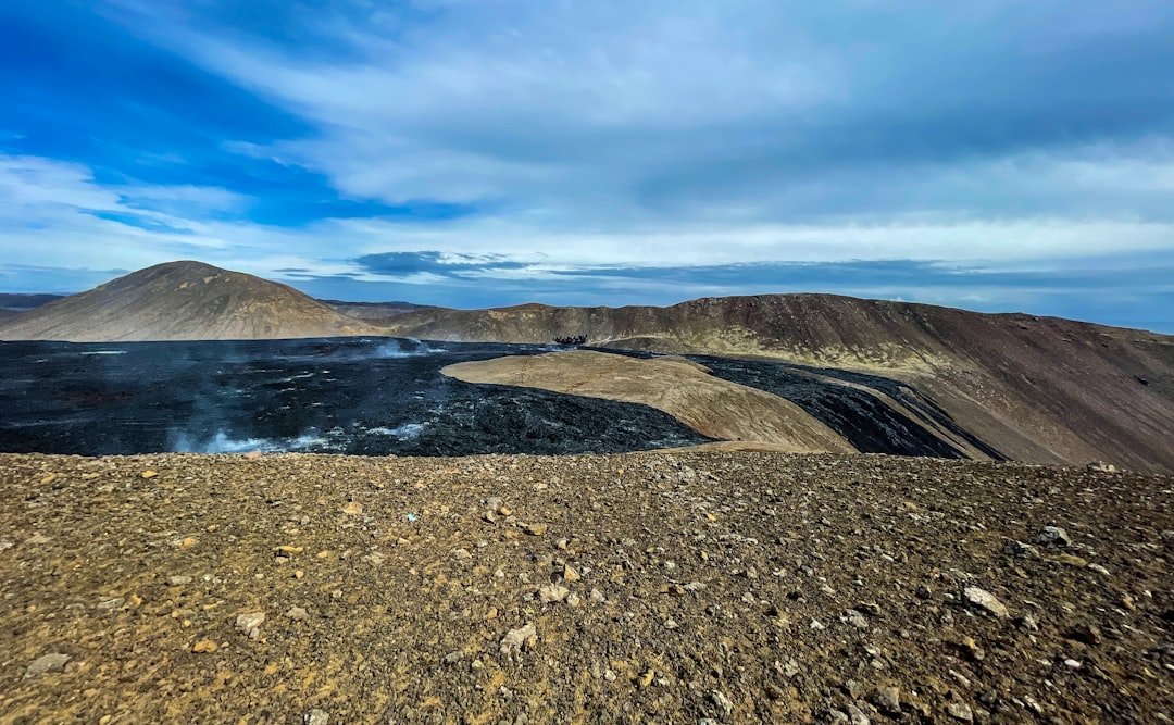 brown mountain near body of water under blue sky during daytime