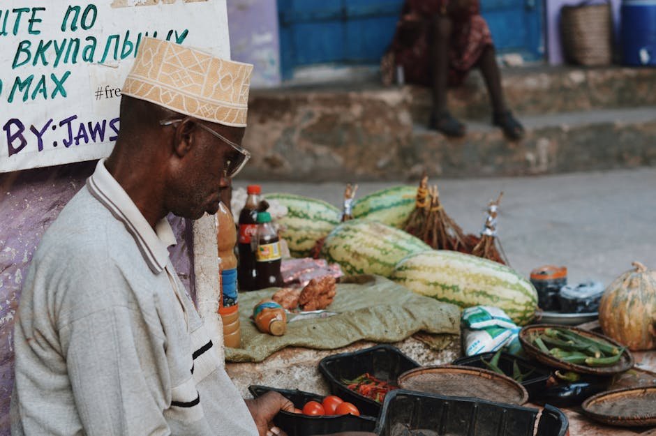A market scene in Zanzibar City featuring a vendor with fresh produce like tomatoes, watermelons, and spices.