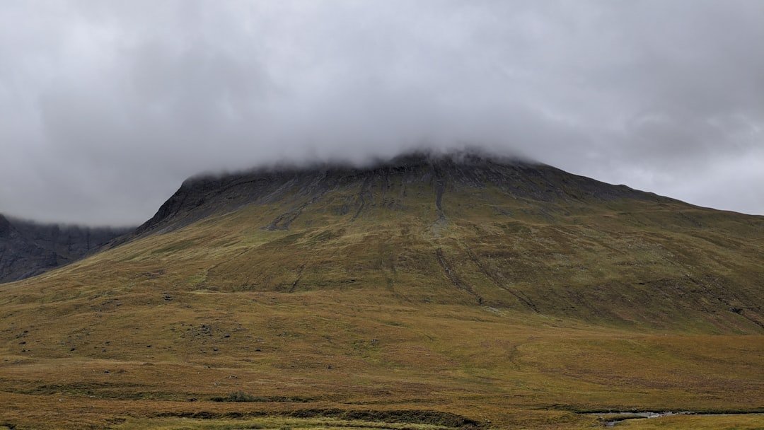 une montagne couverte d'herbe et de nuages par une journée nuageuse