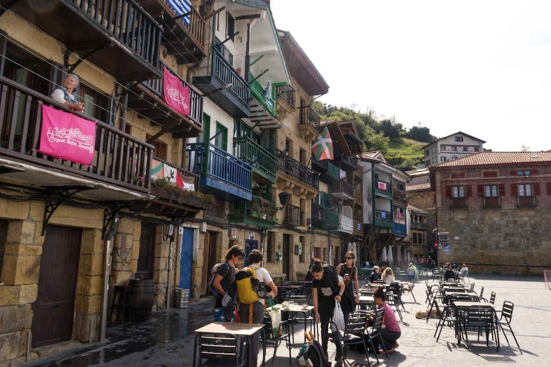 Des gens rassemblés sur une place de village avec des bâtiments.