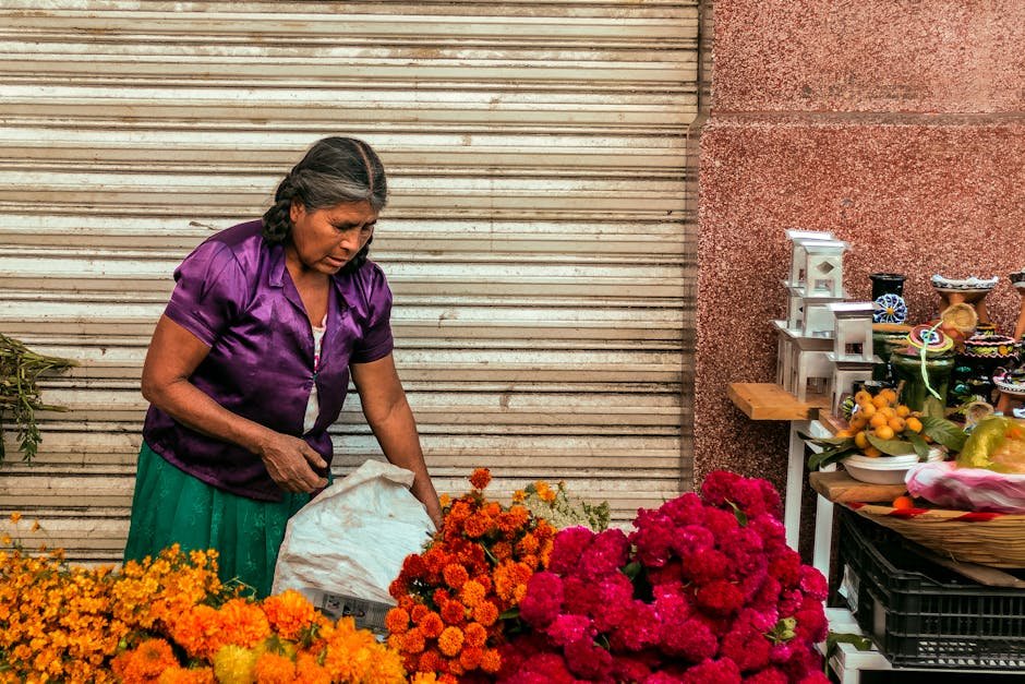 Elderly woman sells vibrant flowers at a market in Oaxaca, Mexico.