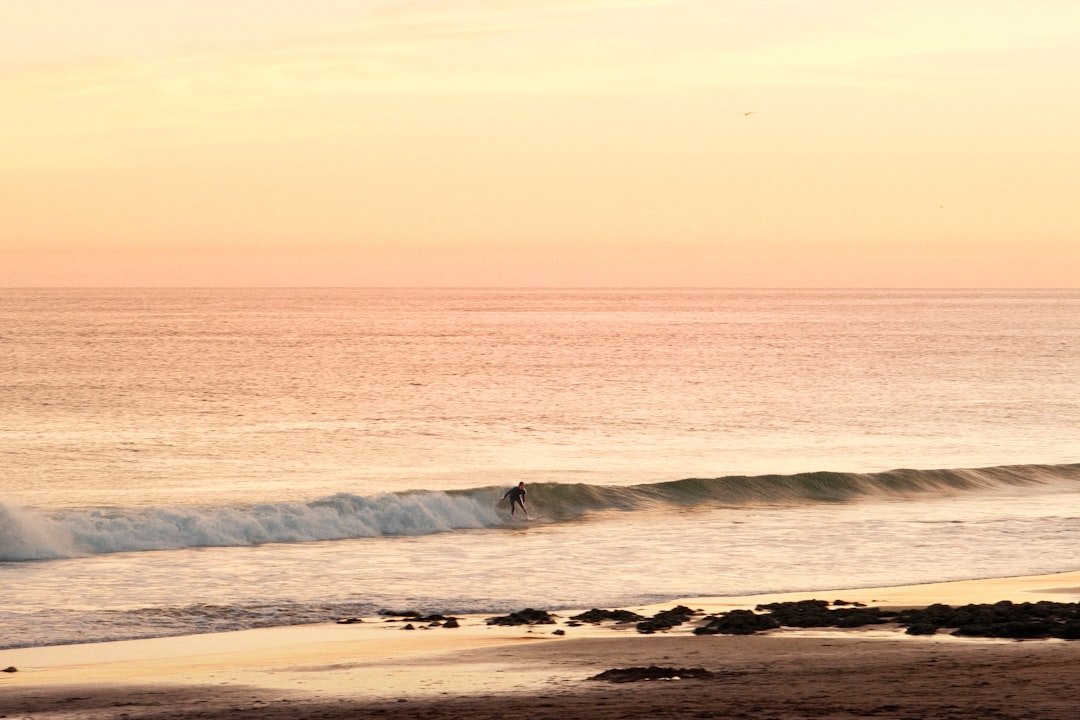 A surfer rides a wave at sunset.