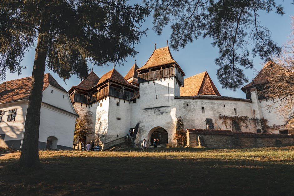 Historic fortified church surrounded by rural landscape at sunset in Romania, showcasing traditional architecture.