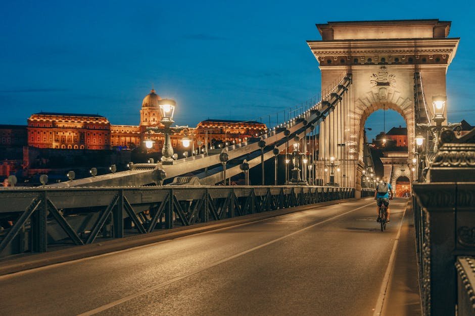 Un ciclista attraversa di notte il Ponte delle Catene Széchenyi illuminato a Budapest.