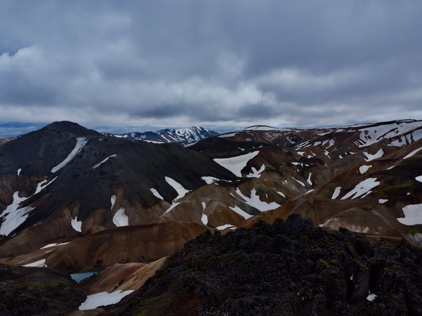 Una splendida vista aerea di montagne innevate nelle Highlands islandesi, che mostra un terreno aspro e nuvole drammatiche.