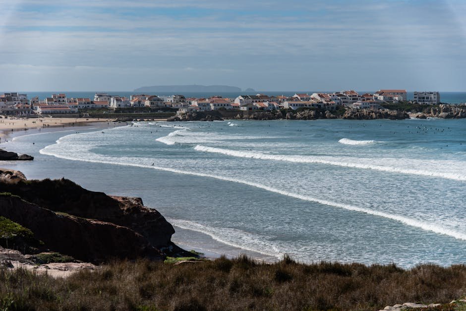 Picturesque view of Peniche's coastline with waves crashing and houses by the Atlantic.