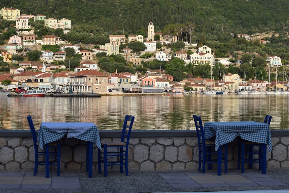 Picturesque dining setup by the sea on a Greek island with beautiful hillside view.